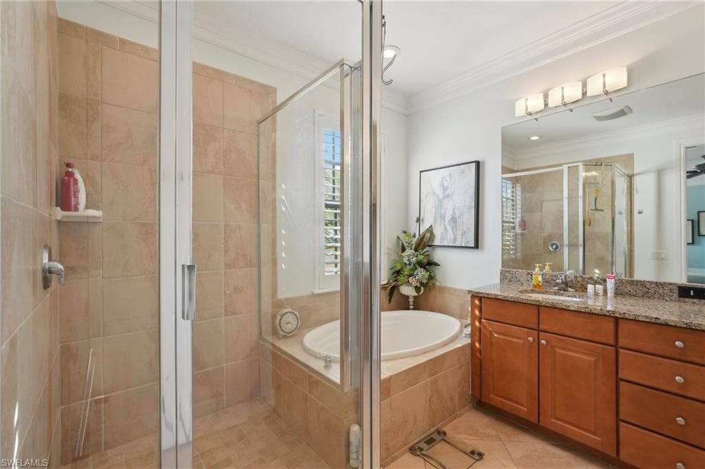 Full bathroom featuring crown molding, tile patterned flooring, vanity, a shower stall, and a garden tub