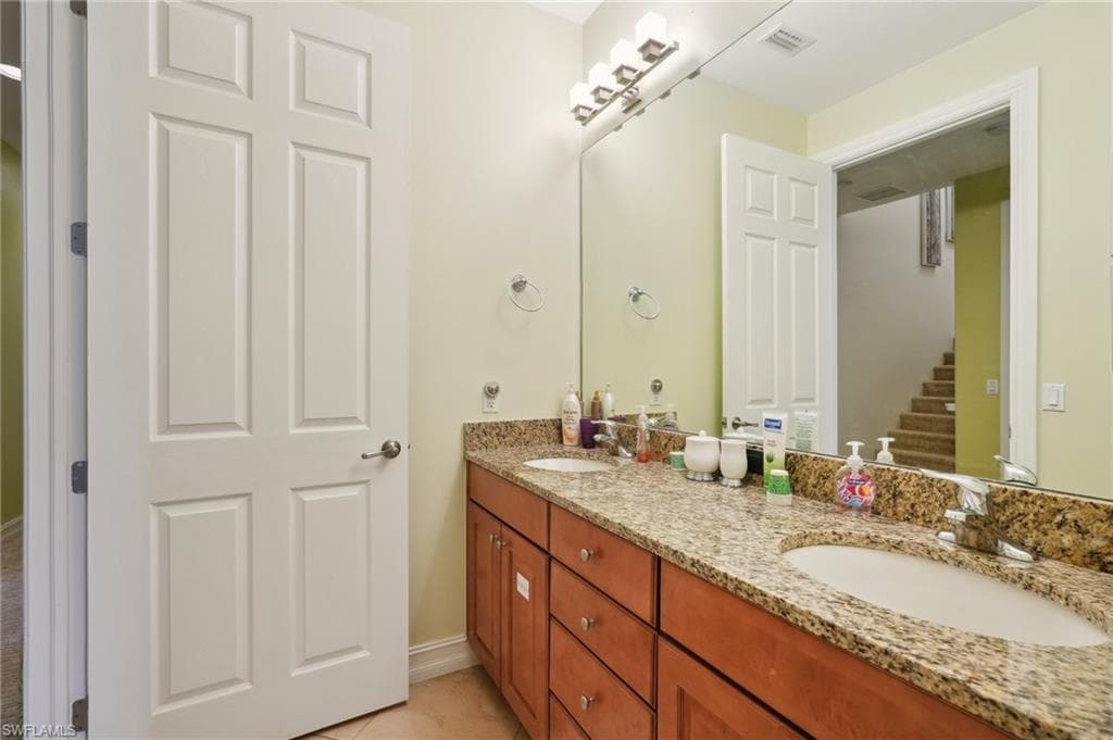 Bathroom with double vanity, a sink, tile patterned floors, and visible vents