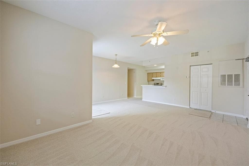 Unfurnished living room featuring light carpet and a ceiling fan