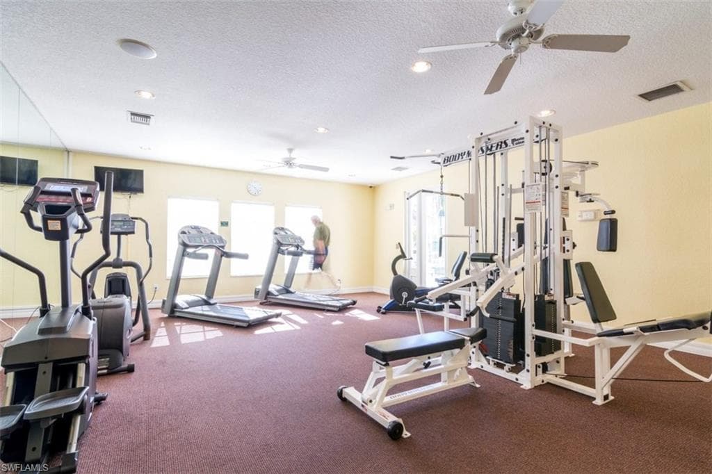 Workout area with ceiling fan, a textured ceiling, and recessed lighting