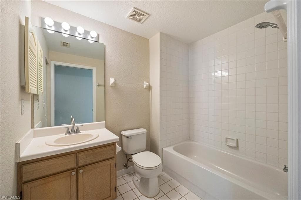 Full bath featuring tile patterned flooring, vanity, shower / bathtub combination, and a textured wall