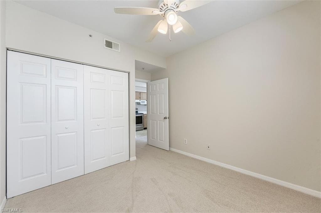 Unfurnished bedroom featuring light colored carpet, a closet, and ceiling fan