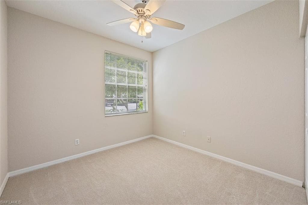 Empty room featuring light carpet and a ceiling fan