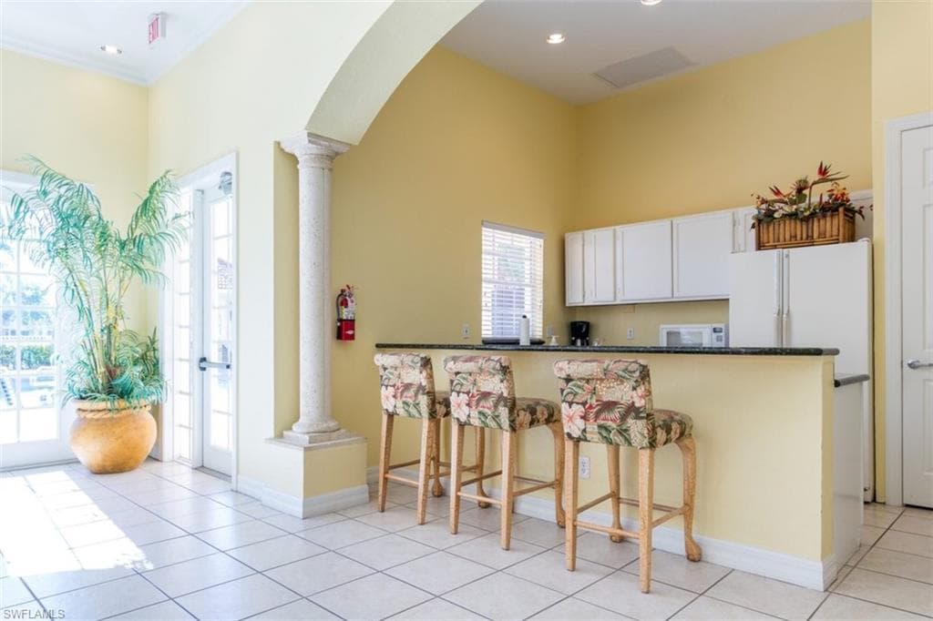 Kitchen with decorative columns, white appliances, healthy amount of natural light, a towering ceiling, and recessed lighting