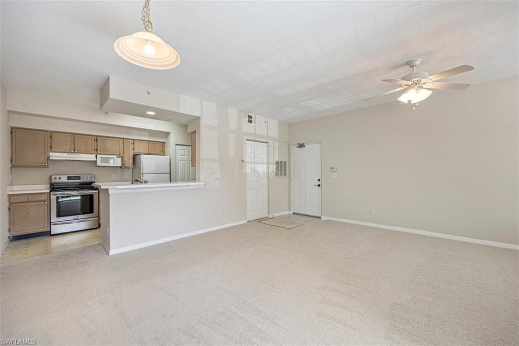 Unfurnished living room with light colored carpet and a ceiling fan
