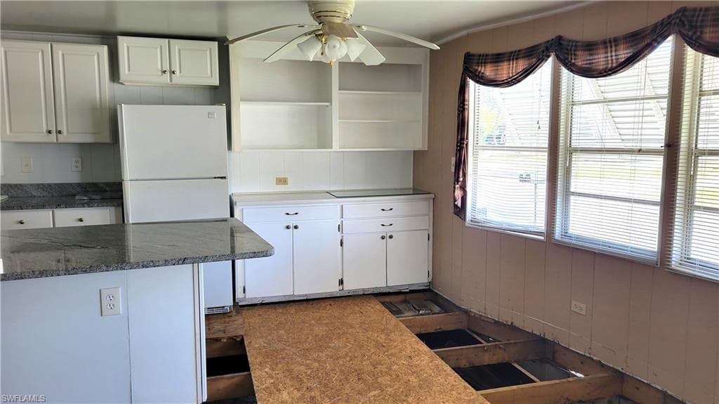 Kitchen featuring freestanding refrigerator, white cabinetry, a ceiling fan, and open shelves
