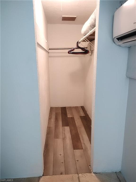 Walk in closet featuring wood finished floors and a wall mounted AC