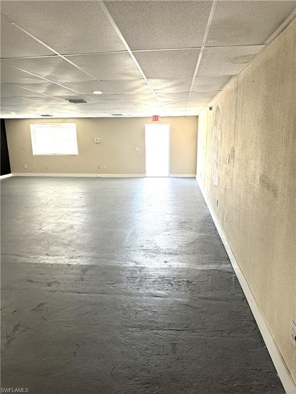 Basement with a wealth of natural light, baseboards, and a drop ceiling