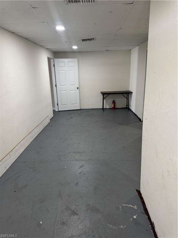 Basement featuring a drop ceiling, visible vents, and baseboards