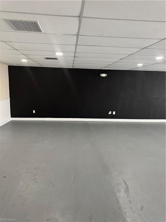 Spare room featuring a paneled ceiling, concrete flooring, and visible vents