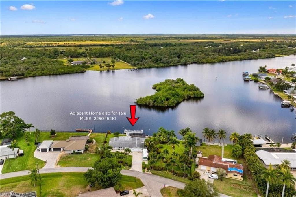 Aerial view of residential area with a large body of water and a heavily wooded area