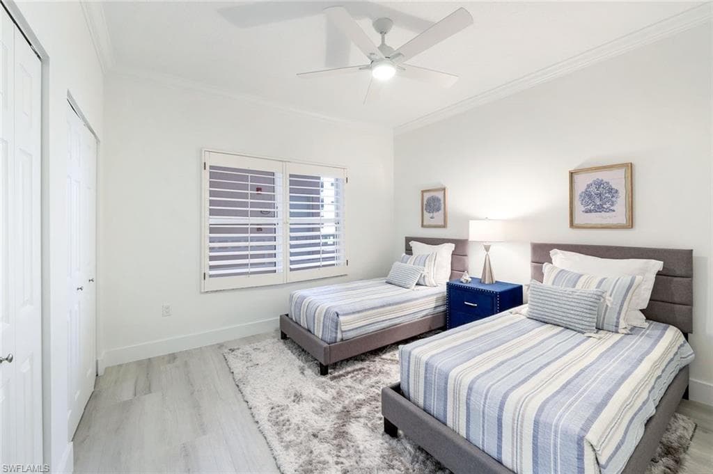 Bedroom featuring wood finished floors, crown molding, baseboards, a closet, and ceiling fan