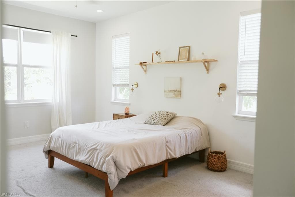 Bedroom with carpet, multiple windows, and baseboards