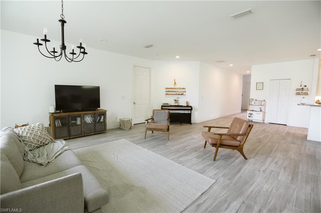 Living area with a chandelier, light wood finished floors, recessed lighting, and baseboards