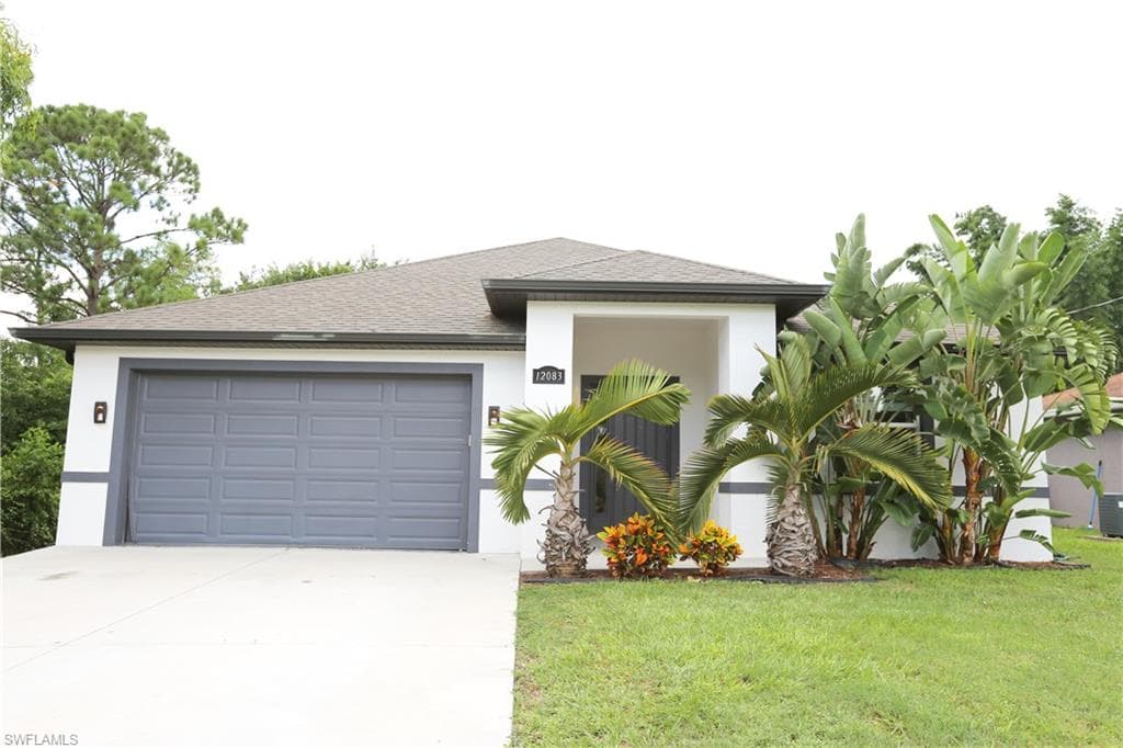 View of front of house featuring driveway, stucco siding, a front lawn, a garage, and roof with shingles