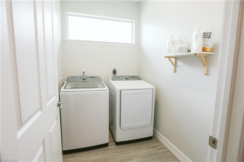 Laundry area featuring separate washer and dryer and light wood finished floors