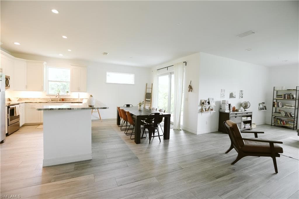 Kitchen featuring appliances with stainless steel finishes, a sink, white cabinetry, light wood-style flooring, and recessed lighting