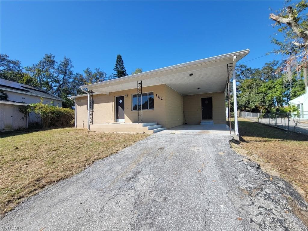 View of front of house with driveway, an attached carport, and a porch