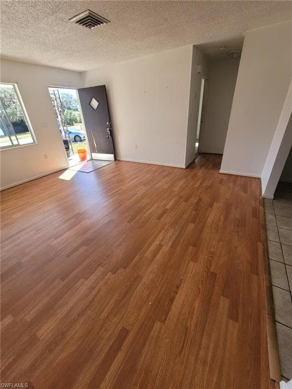 Unfurnished living room with a textured ceiling and light wood-style flooring