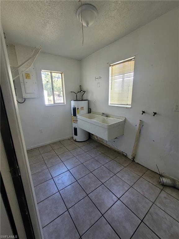 Full bath with light tile patterned flooring, electric water heater, a textured ceiling, and electric panel