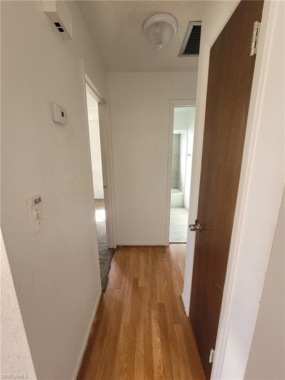 Hallway with light wood-style flooring and a textured ceiling