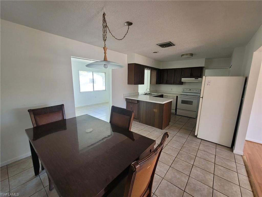Dining space with light tile patterned flooring and a textured ceiling