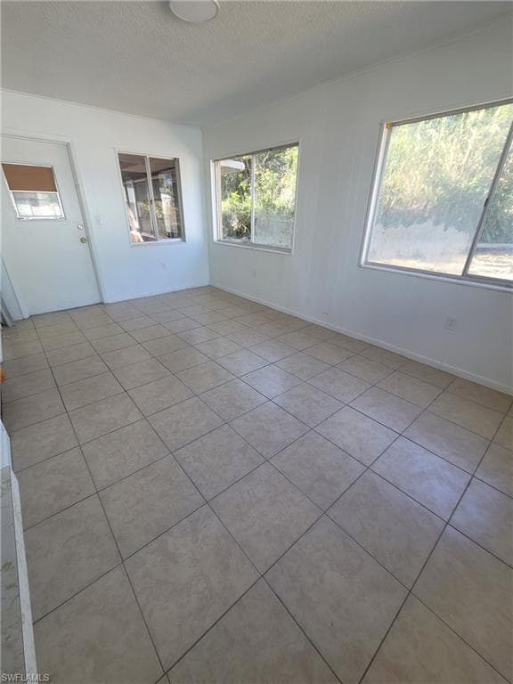 Empty room featuring light tile patterned flooring and a textured ceiling