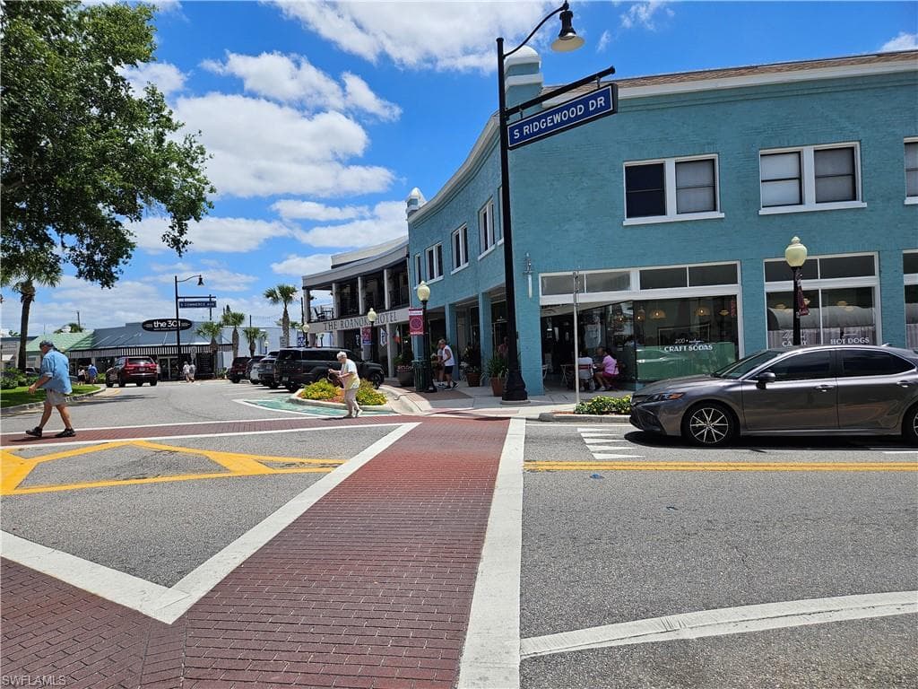 View of asphalt street with curbs, street lights, and sidewalks
