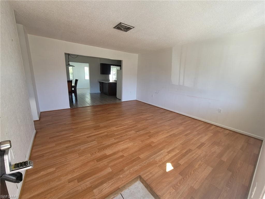 Empty room featuring light wood-type flooring and a textured ceiling