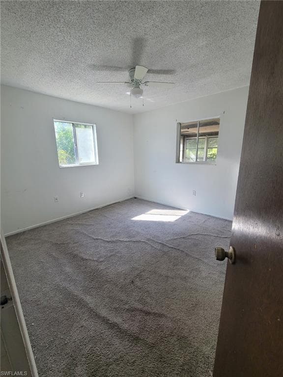 Carpeted spare room with ceiling fan, healthy amount of natural light, and a textured ceiling