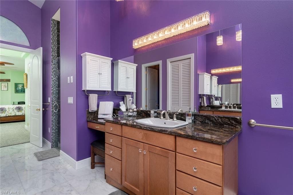 Master Bathroom downstairs with linen closet, dual vanities & sinks, jetted tub, rain shower, private toilet room, marble flooring, and high vaulted ceiling