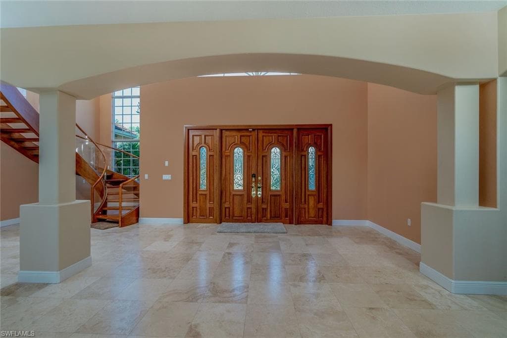 Foyer featuring arched walkways, stairs, Mahogany/stained glass impact front doors
