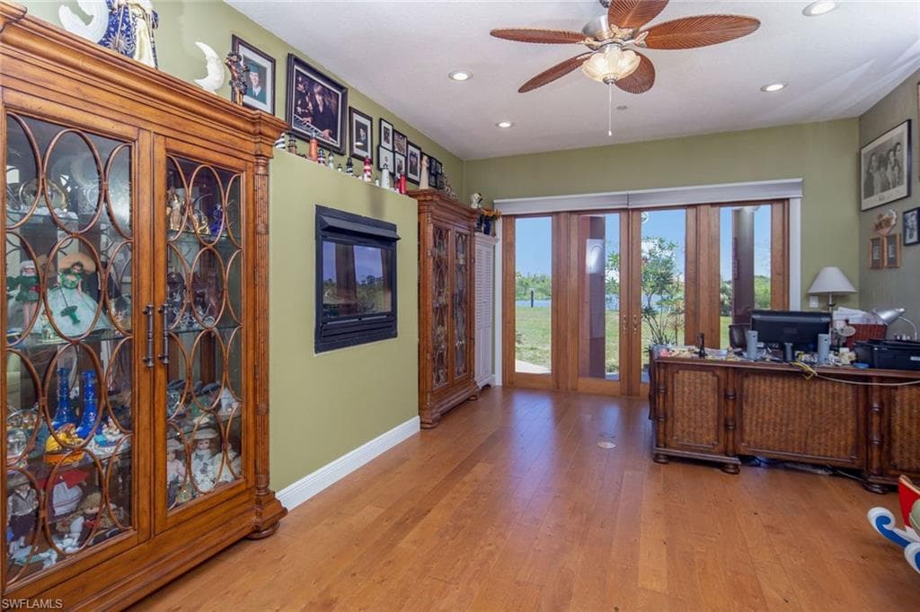Office with french doors, water view, real wood flooring, recessed lighting, and ceiling fans