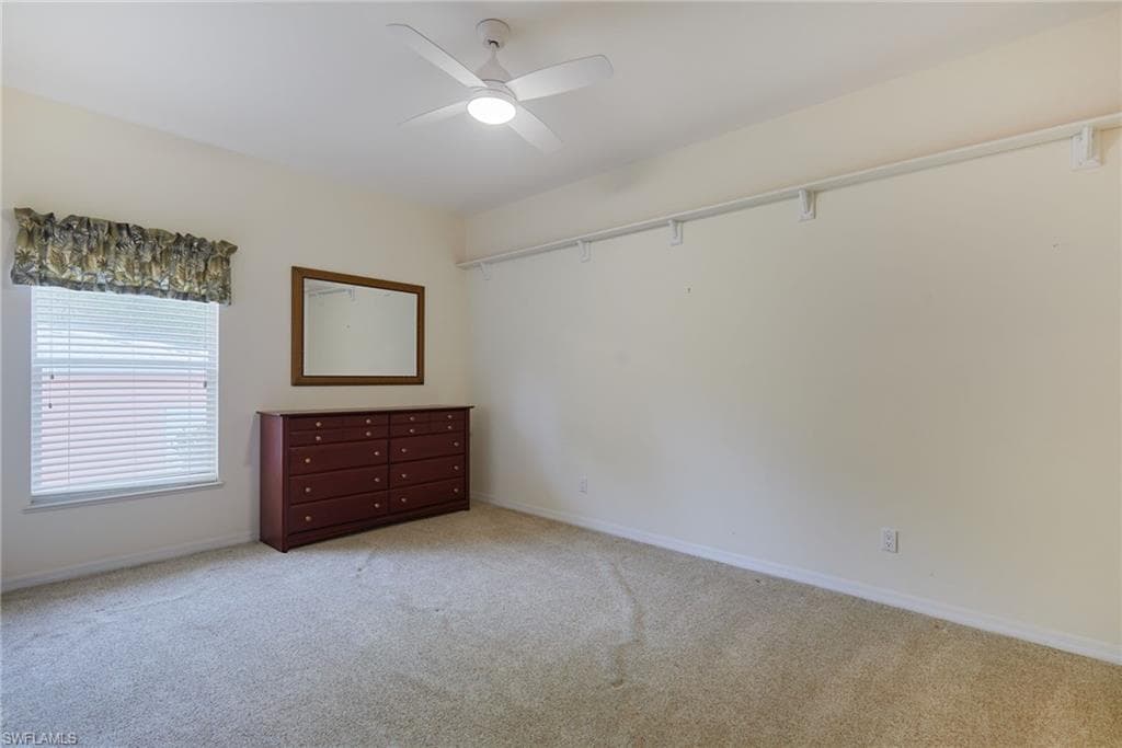 Unfurnished bedroom with light colored carpet, baseboards, and ceiling fan