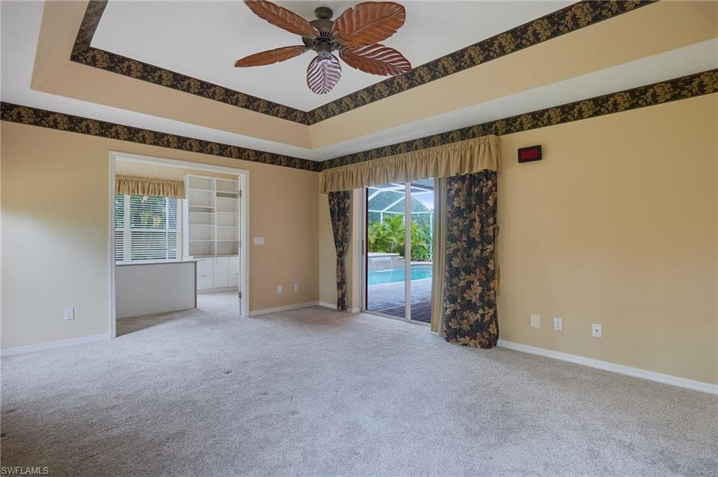Spare room with light colored carpet, plenty of natural light, a ceiling fan, and baseboards