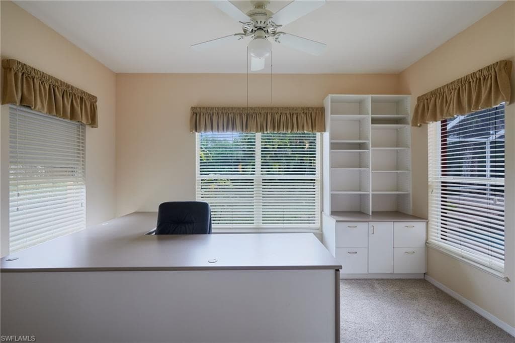Unfurnished office with light carpet, ceiling fan, and baseboards