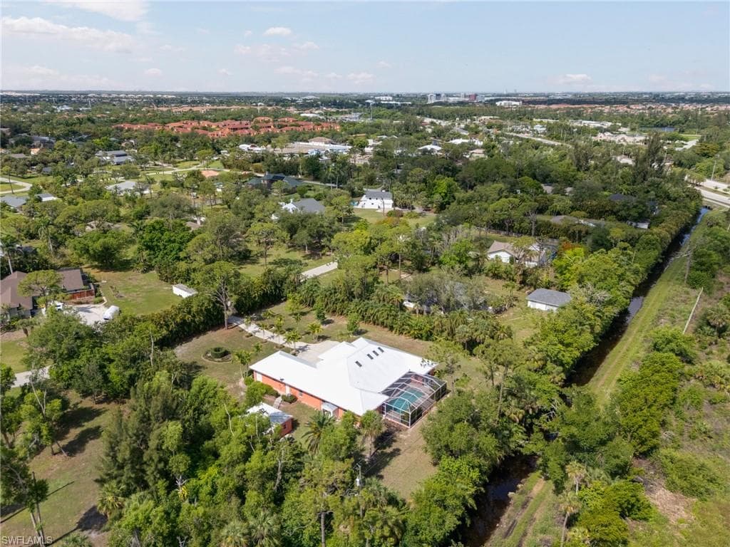 Aerial view of property and surrounding area with a tree filled landscape