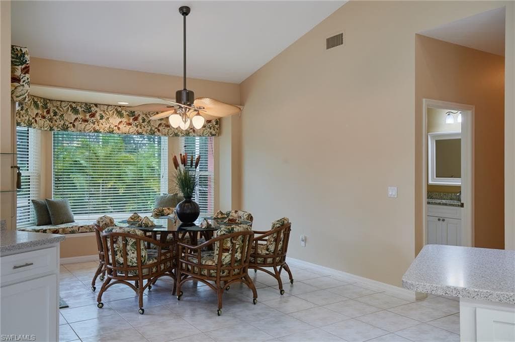 Dining room with a ceiling fan, light tile patterned flooring, baseboards, and lofted ceiling