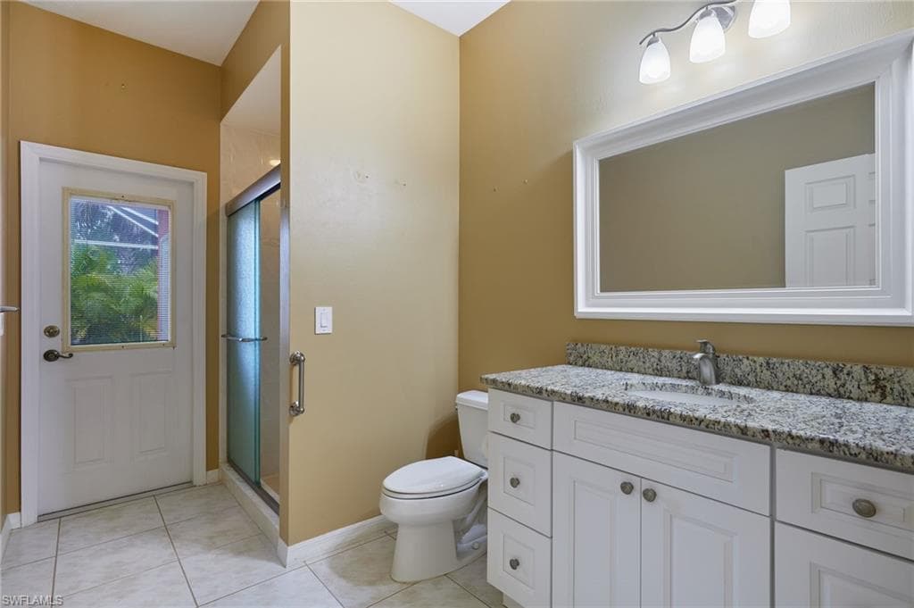 Bathroom with vanity, toilet, a stall shower, and tile patterned flooring