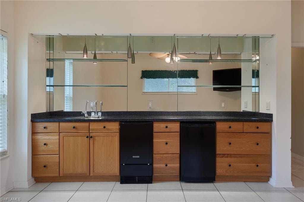 Kitchen featuring a sink, brown cabinetry, baseboards, and dark stone countertops