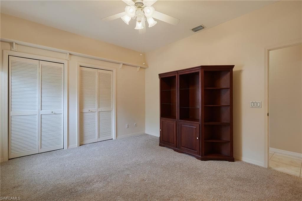 Unfurnished bedroom with carpet flooring, multiple closets, a ceiling fan, and baseboards