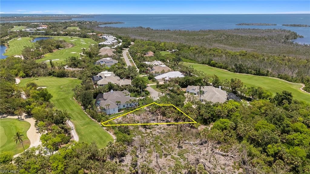 Aerial view of residential area featuring a golf club, a large body of water, and property boundaries highlighted