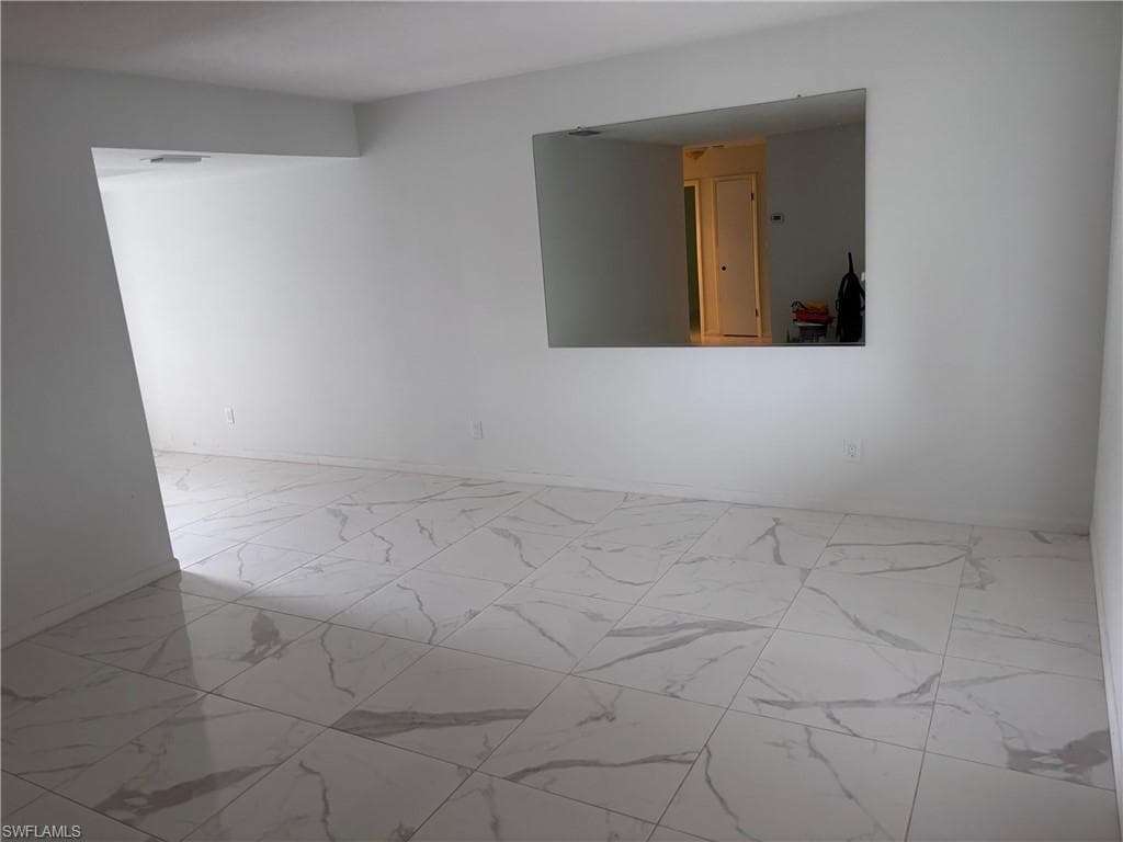 Spare room with marble look tiles and baseboards