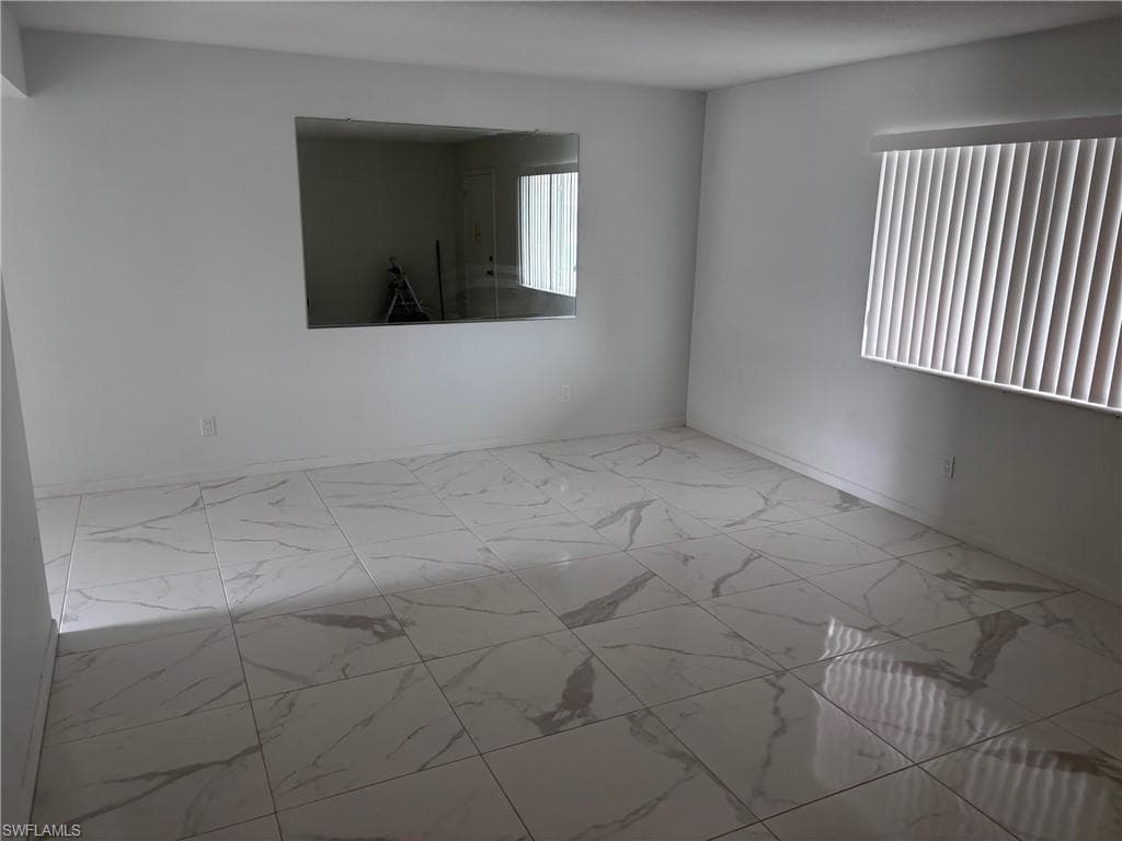Spare room featuring marble finish floors and baseboards