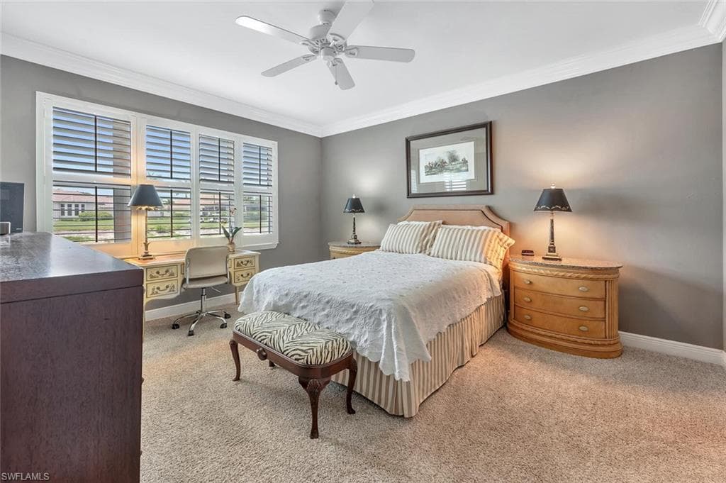 Bedroom featuring light carpet, baseboards, crown molding, an office area, and ceiling fan