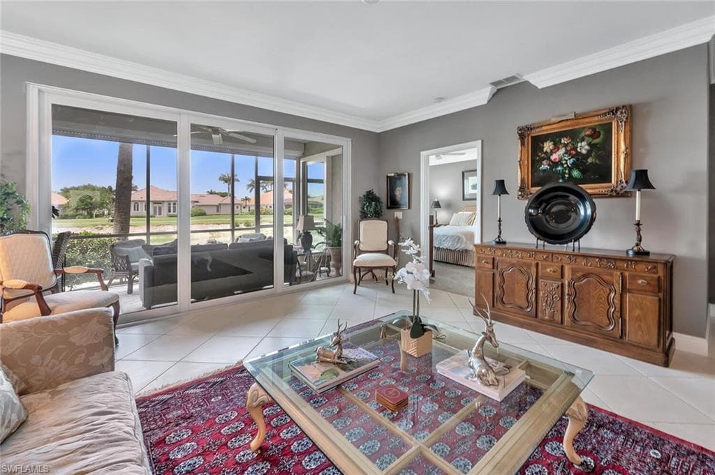 Living room featuring light tile patterned floors, plenty of natural light, crown molding, and ceiling fan