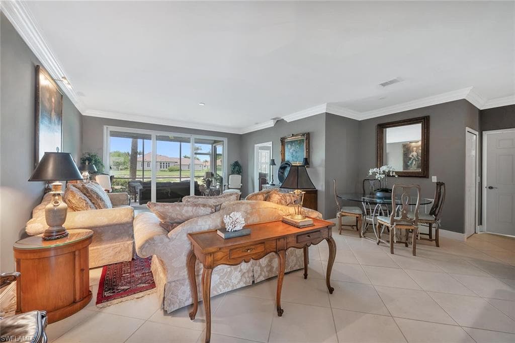 Living room featuring crown molding, light tile patterned floors, and baseboards