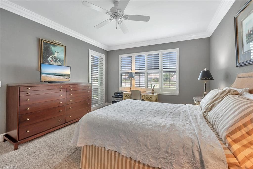 Carpeted bedroom with crown molding and a ceiling fan