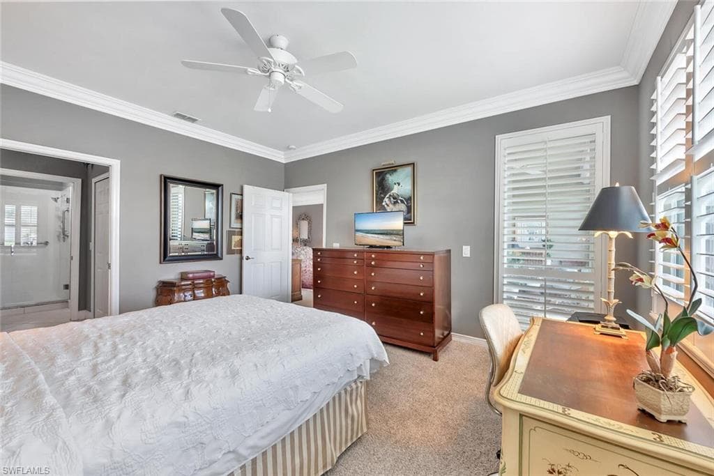 Bedroom with crown molding, light carpet, an office area, ceiling fan, and connected bathroom