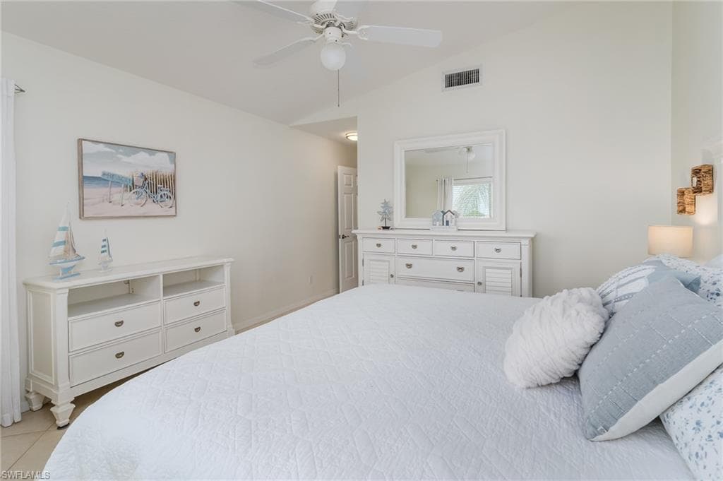 Tiled bedroom featuring vaulted ceiling and a ceiling fan